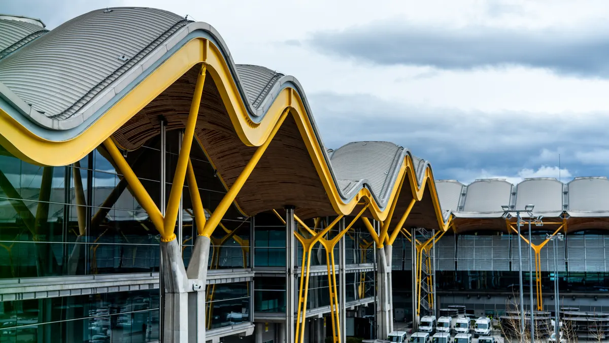 Vue frappante d'un terminal d'aéroport moderne au toit ondulé et aux supports jaune vif.